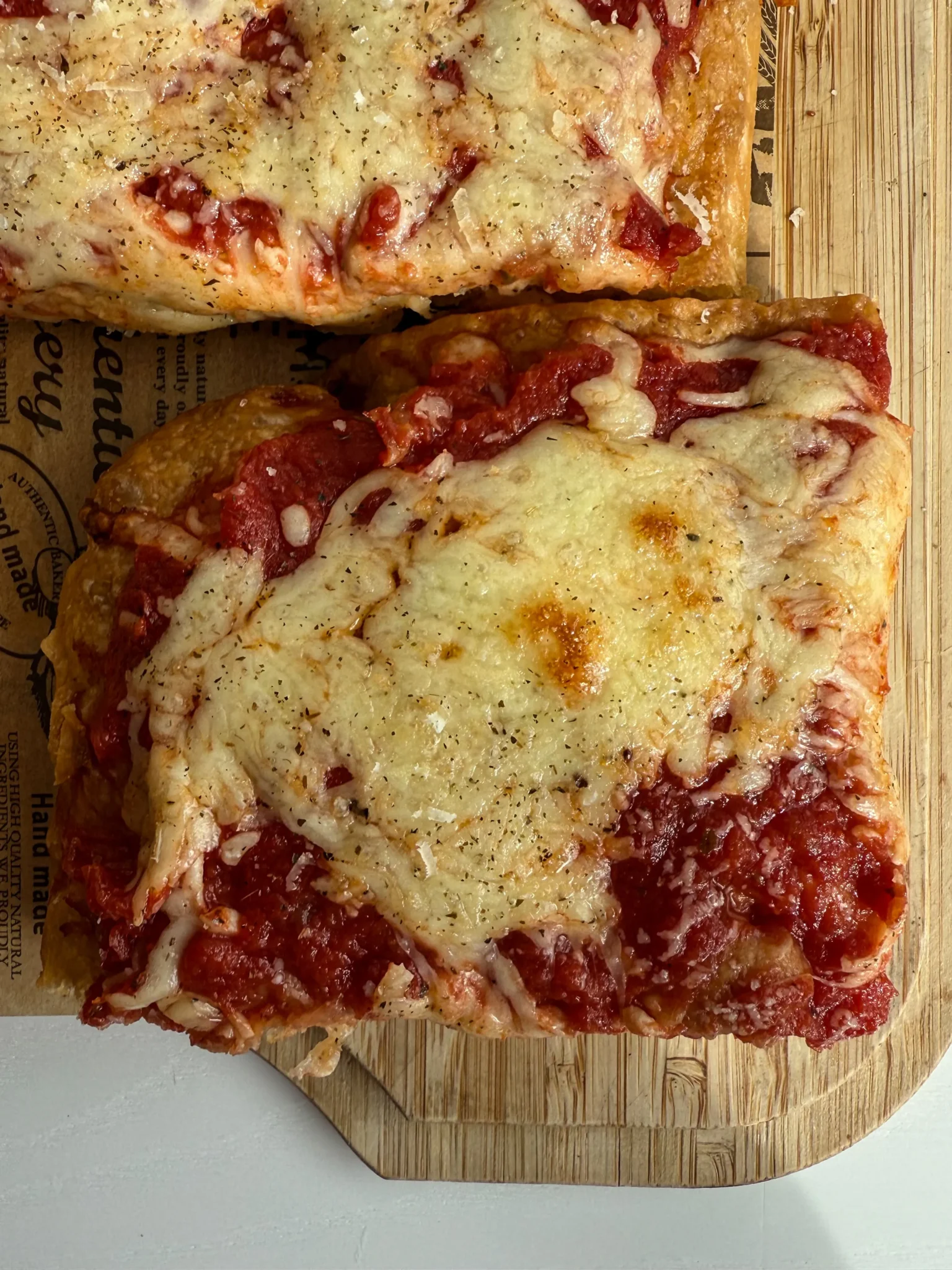 Cheesy rectangular pizza on wooden board